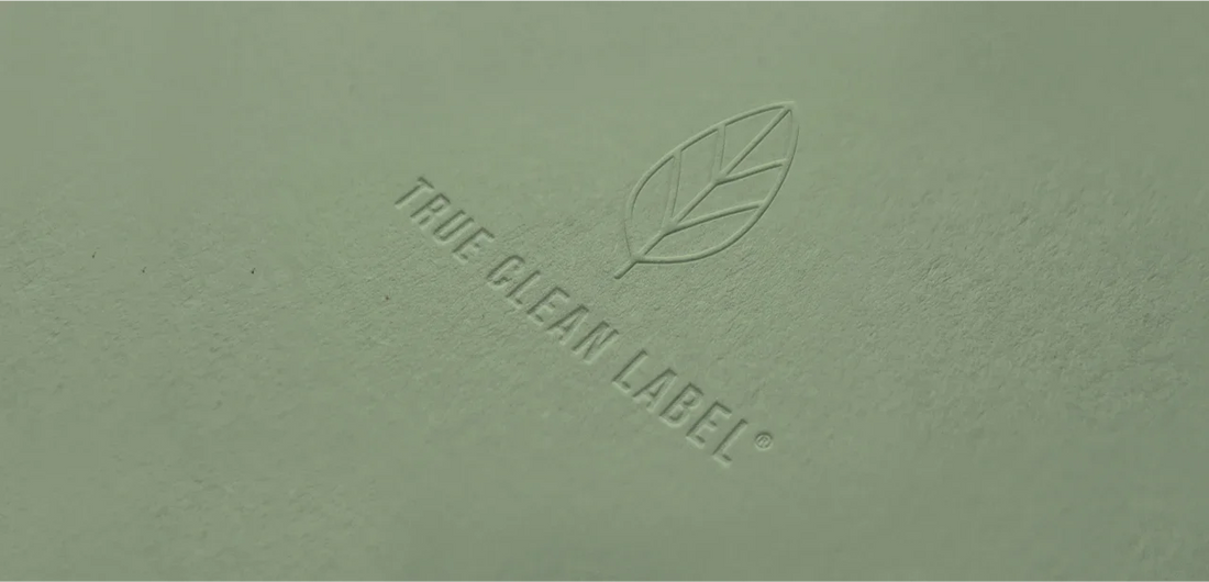 True Clean Label® embossed logo with leaf icon on textured green paper, symbolizing purity and natural ingredients.